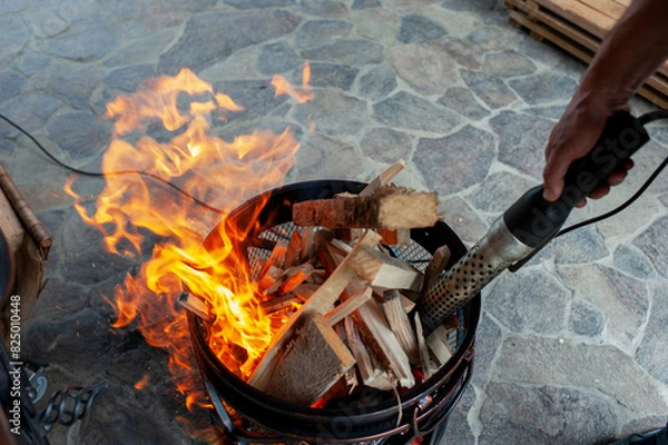 Fototapeta The male hand and warm fireplace with lots of trees ready for barbecue