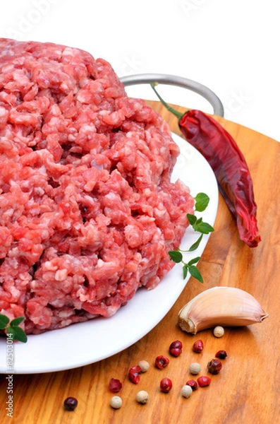 Fototapeta minced meat with pepper, thyme and garlic on cutting board isola
