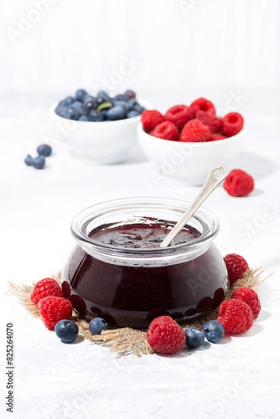 Obraz raspberry and blueberry jam in a glass jar, vertical