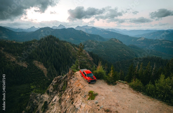 Fototapeta Aerial shot of shot of a pickup truck standing on the cliff with a backdrop of North Cascades Mountains in Snoqualmie Pass, Washington State. 