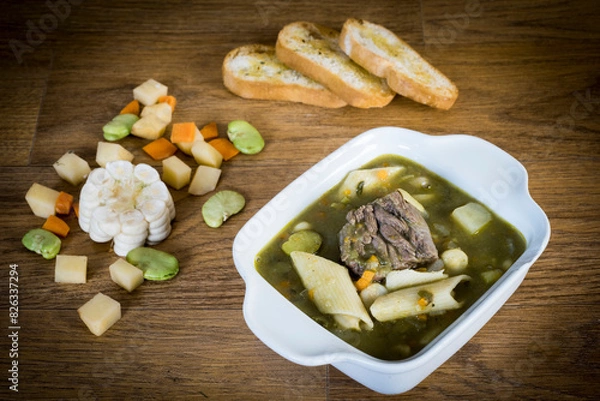 Obraz A bowl of Peruvian menestron soup. With chunks of meat, noodles, chopped carrots, corn and coriander to give it the green color.