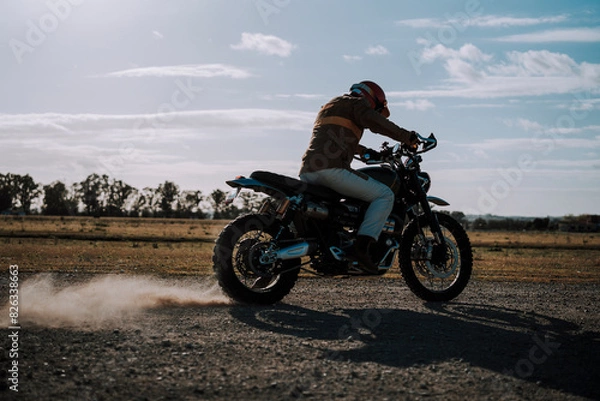 Fototapeta a man riding a dirt bike in a field on a sunny day