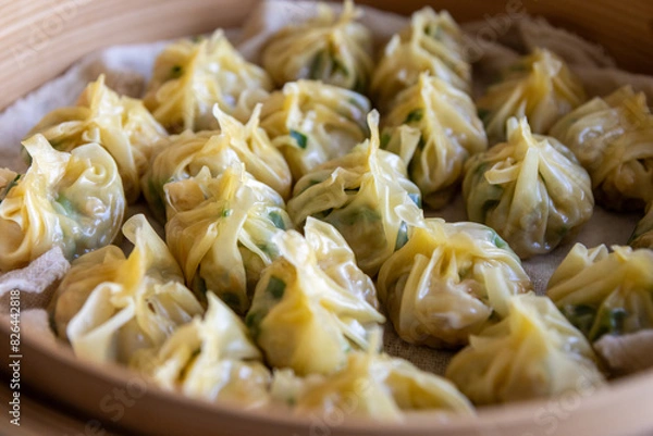 Fototapeta Steamed dumplings - vibrant green herbs and succulent meat visible - nestled in a bamboo steamer with a glossy appearance. Taken in Toronto, Canada.