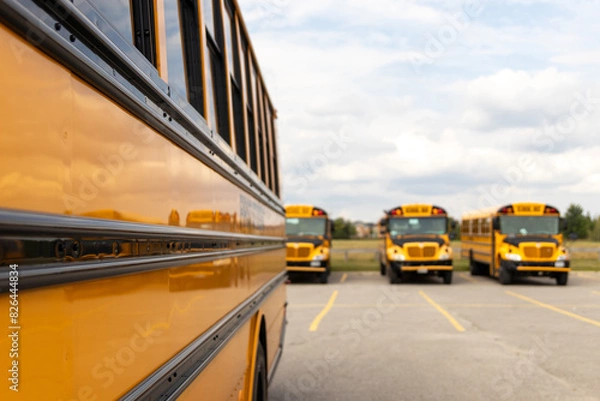 Fototapeta Side view close-up of yellow school bus - parked - sunny day with clouds in sky. Taken in Toronto, Canada.