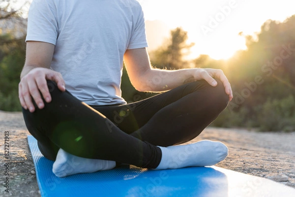 Fototapeta Closeup of an unrecognizable young man practising yoga exercises in nature