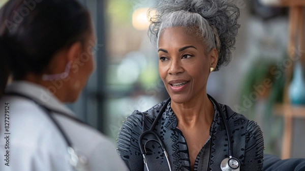 Fototapeta Mature woman with a stethoscope, consulting a patient online