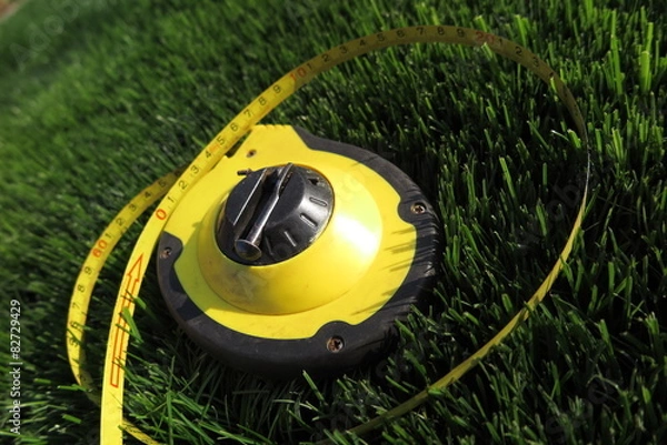 Fototapeta Measuring tape lying on the fresh mown lawn grass