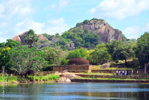 Fototapeta Natural setting of ancient ruins, water body, tropical vegetation and a rock mountain as a backdrop