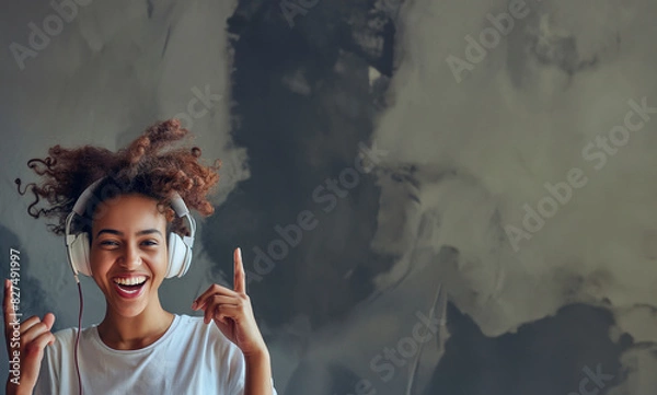 Fototapeta Cheerful individual with headphones on, smiling widely and gesturing towards the headphones