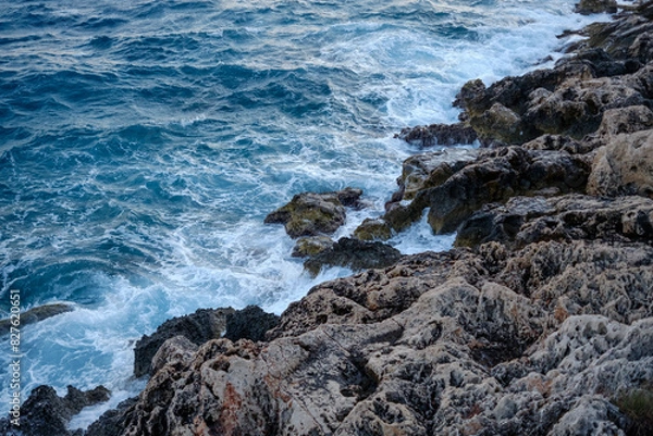 Fototapeta Beautiful view of water crashing on the rocky shore. Wave splashing against stones on shore close up.