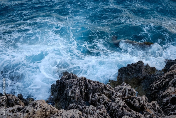Fototapeta Beautiful view of water crashing on the rocky shore. Wave splashing against stones on shore close up.
