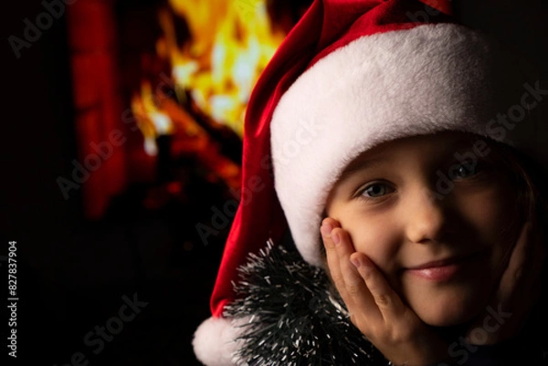 Obraz Close-up of girls in Santa's hat on background of fireplace