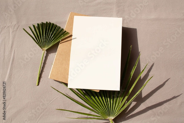 Fototapeta Empty writing notebook and palm leaf on a gray background with contrasting shadows. Lifestyle. Flat Lay