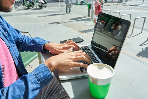 Fototapeta unrecognizable hands of a man sitting in a coffee shop using his laptop for work or chatting