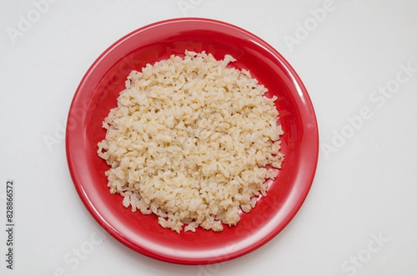Obraz Plate of cooked brown rice on a white background