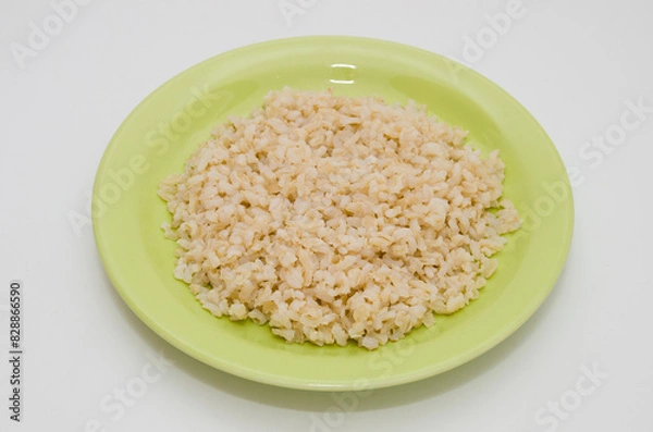 Obraz Plate of cooked brown rice on a white background