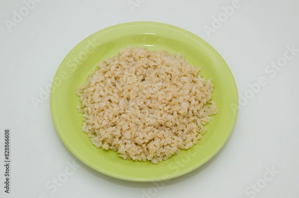 Obraz Plate of cooked brown rice on a white background