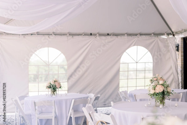 Obraz A tented backyard wedding reception with white tables and simple flower arrangement in the center of each table. 