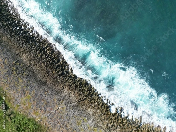 Fototapeta Rocky shore if a beach in San Andres Island, Colombia. The waves crushes against the shore and produce white foam and beautiful patterns