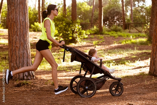Obraz Beautiful young woman runs with a stroller.