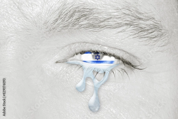 Fototapeta Crying eye with the flag of Israel in iris on black and white face. Concept of sadness for Israel pain
