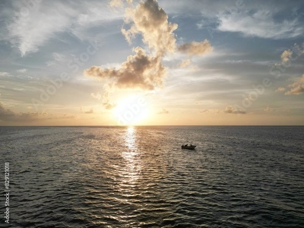 Fototapeta Beautiful sunset scene with the shilouette of a boat with two people. View from above with aereal view from a drone. Picture from san andres islands, Colombia.