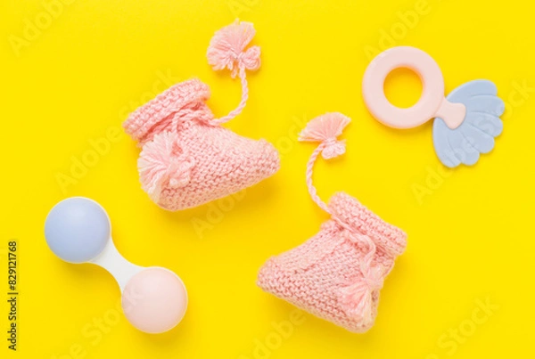 Fototapeta Pink baby booties and rattles on color background, top view