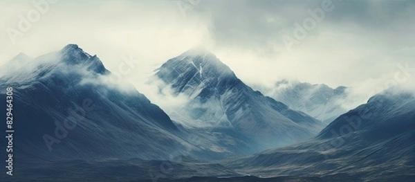 Fototapeta Dramatic skies and high peaks create a vast mountain scene with an incredible copy space image