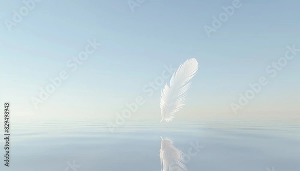 Fototapeta A serene white feather gently floating above a calm, reflective body of water under a clear blue sky.