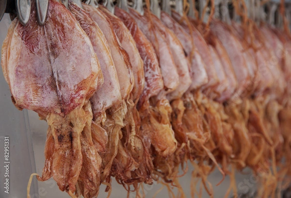 Obraz Stock Photo - Close up dried squid hanging in row waiting for cu