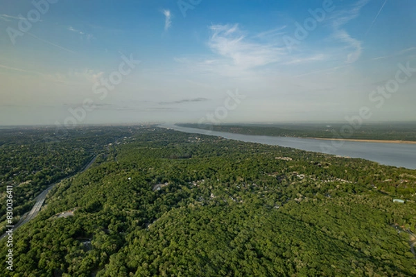 Fototapeta Looking Towards a City in the Distance Over a Green Forest Between a Highway and River