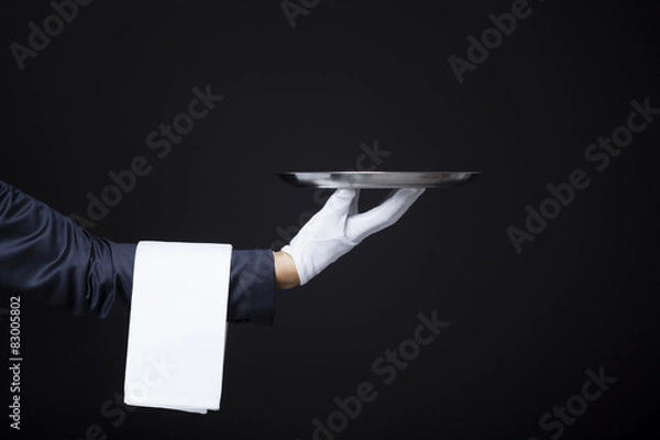 Obraz Image of a waiter hand holding a tray on dark background