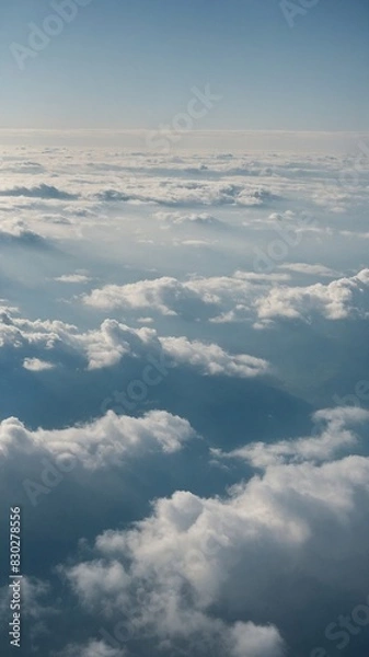 Fototapeta Vast expanse of clouds blankets view, with varying densities, altitudes creating dynamic texture against clear blue sky. Sunlight casts soft shadows, highlights on clouds.