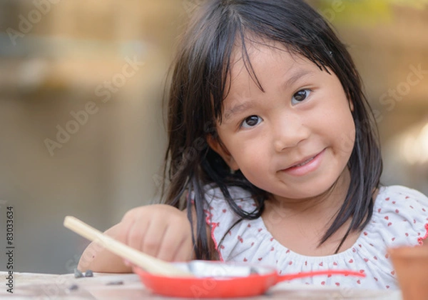 Obraz Smiling little girl plays cook on the table