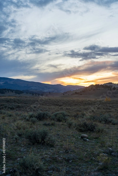 Fototapeta Sunset in the Lamar Valley in Yellowstone National Park in Montana and Wyoming on a beautiful fall evening. Sun sets over the mountains and sagebrush with a colorful sky illuminating the landscape.
