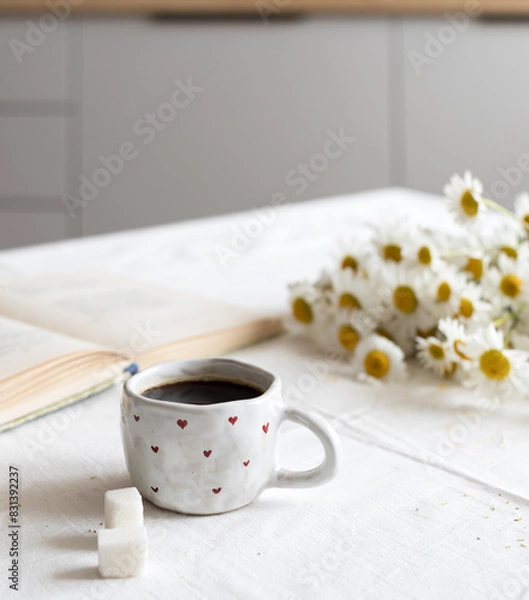 Obraz Front view: a cup of hot coffee, with sugar cubes, standing on the kitchen table in the morning light. The concept of a homemade breakfast.
