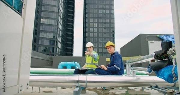 Fototapeta civil engineer Construction manager and manual worker inspector foreman in safety helmet holding laptop meeting conversation about project work at rooftop of building construction site