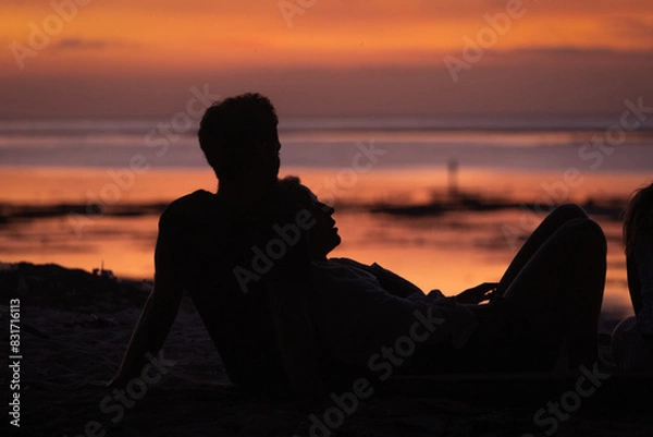 Obraz Couple watching the sunset on the beach.