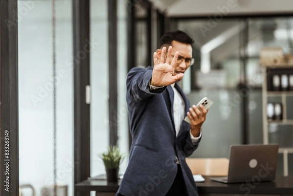 Fototapeta Middle-aged Asian businessman in formal suit working diligently at his desk. seasoned business and investment consultant, specializing in strategic portfolio management and financial analysis.