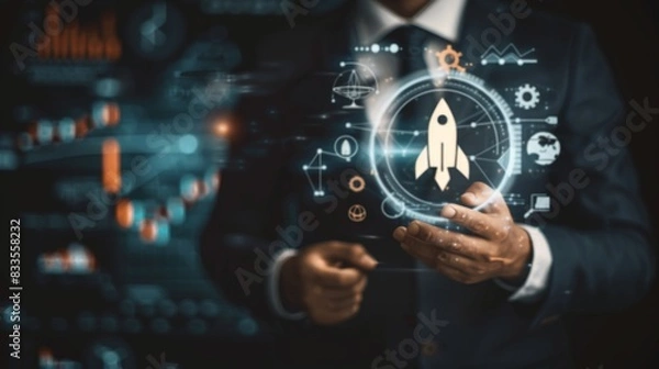 Fototapeta Businessman with digital interface with rocket startup, graph, diagram. Dark background