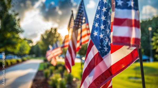 Fototapeta a row of American flags displayed prominently, fluttering in the wind. The scene evokes a sense of patriotism and pride, with the vibrant red, white, and blue colors standing out against the sky.