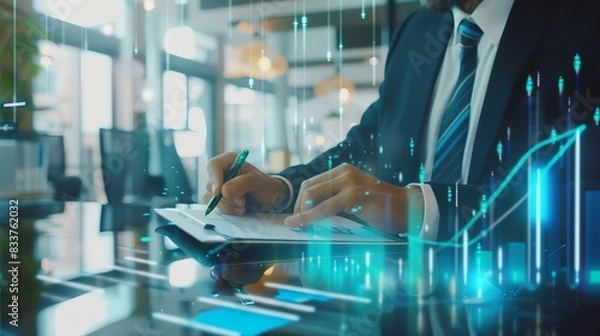 Fototapeta Businessman analyzing financial data in modern office with digital graphics overlay, representing finance, investment, and technology concepts.