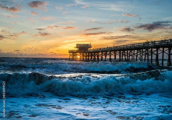 Fototapeta Cocoa Beach Pier on the beach with waves at sunrise