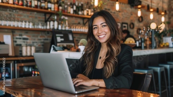 Obraz Happy young Latina businesswoman in suit working with laptop in a cafe or bar smiling confidently, for business owner, self employment, work from home, manager, small business, remote working concept.