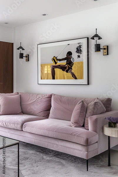 Fototapeta A framed artwork of an athlete in midb area hanging on the wall above sofa, with light purple velvet fabric and black metal legs, placed against a white wall.The room also features minimalist lighting