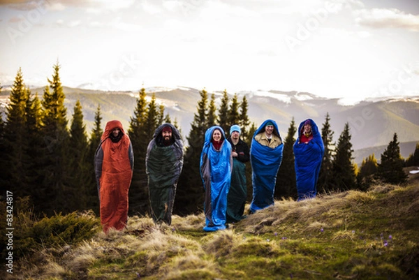 Fototapeta group of hikers jumping in sleeping bags in mountains 