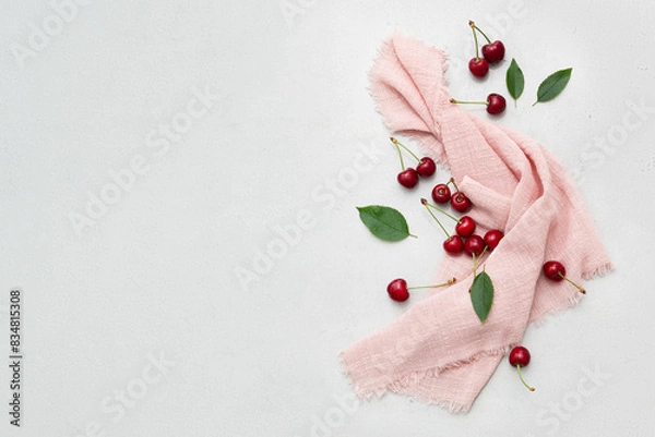 Fototapeta Ripe delicious cherries on a pink napkin on a light gray background. Top view. Space for text.