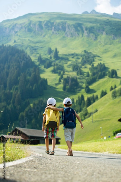 Fototapeta Two little children, boy brothers with backpacks travel on the road to scenic mountains