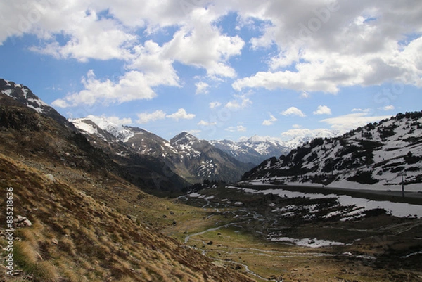 Obraz Una preciosa vista de un lago de alta montaña con restos de nieve cielo azul y nubes