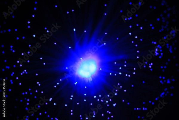 Fototapeta Abstract navy blue flash on a black background and glowing particles